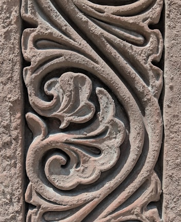 Intricate stone carving features swirling floral and abstract patterns, showcasing detailed craftsmanship with a weathered texture.