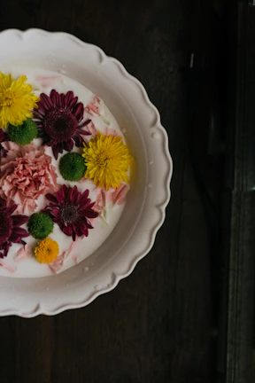 A bright yellow ceramic plate set on a rustic wooden table with fresh flowers.