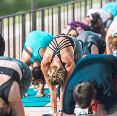 Outdoor yoga class at sunrise with participants stretching on mats.