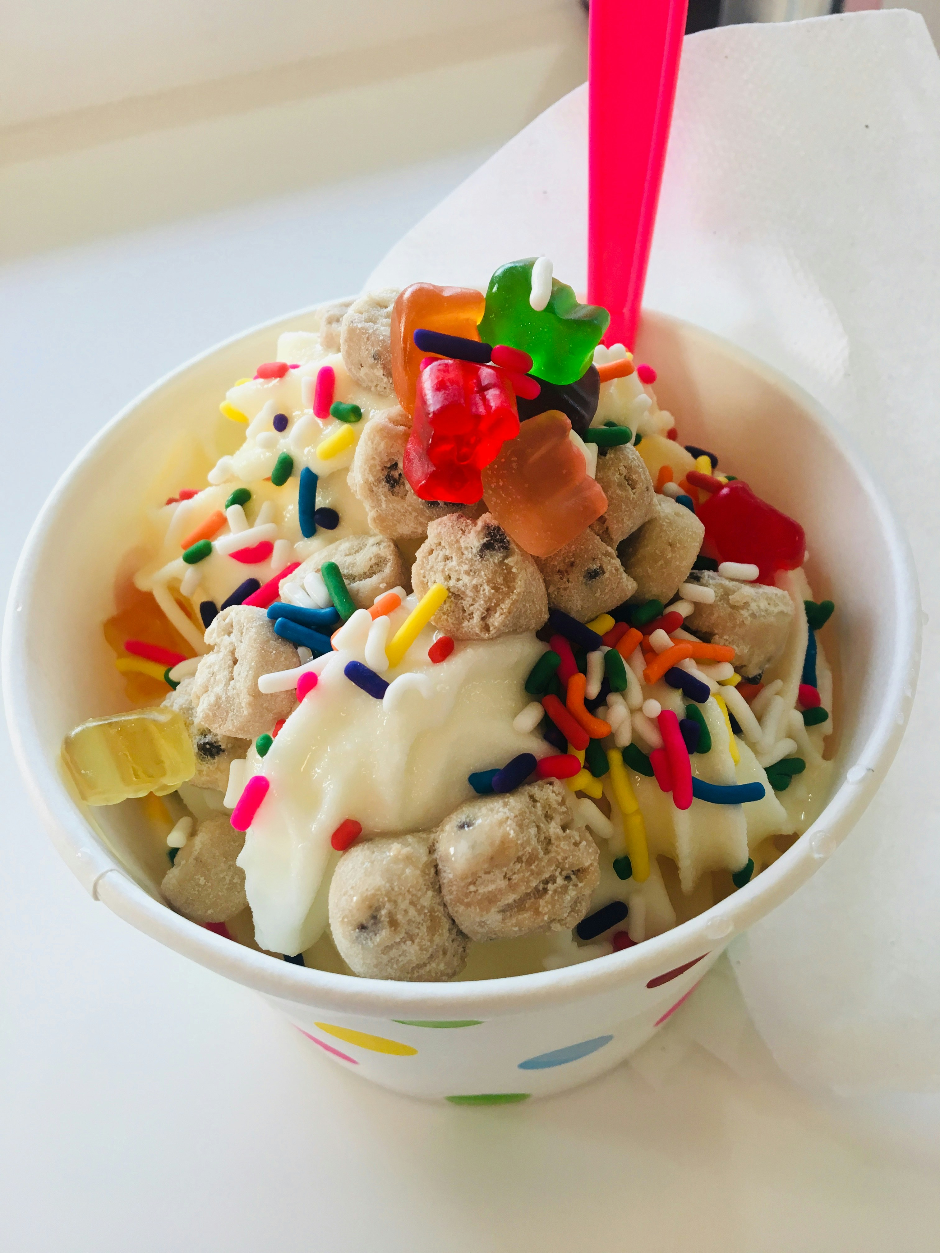 Small colourful frozen yoghurt cup with rainbow sprinkles, marshmallows and chocolate chips for kids