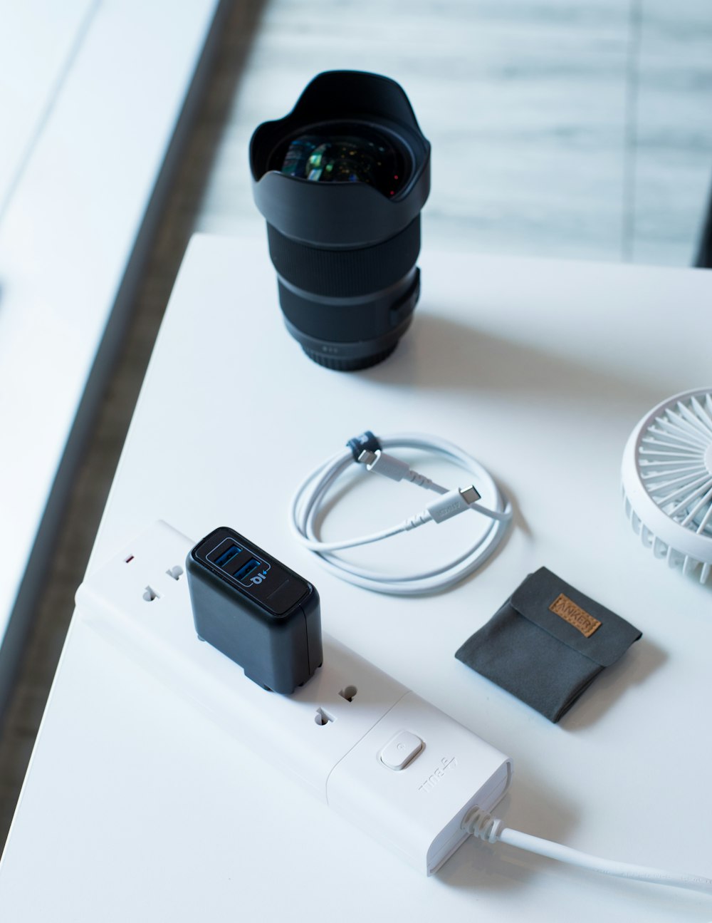 white travel adapter beside camera lens on white surface