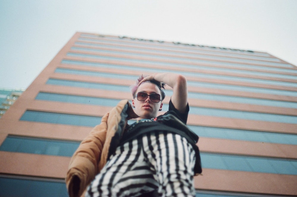 low-angle photography of man beside brown building