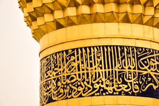 Close-up of intricate Arabic calligraphy carved into mosque stonework.