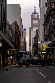 A flatbed truck parked at a cityscape backdrop.