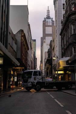 A sturdy cargo truck driving through a city street during the day.