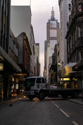 A sturdy cargo truck driving through a city street during the day.
