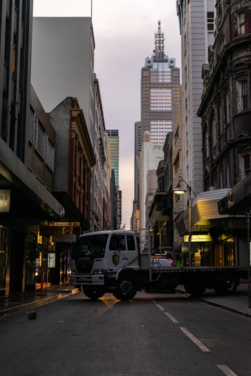 A sturdy cargo truck driving through a city street during the day.