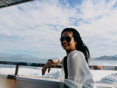 Close-up of a local skipper smiling warmly aboard a luxury boat, with the sun setting over the sea behind him.