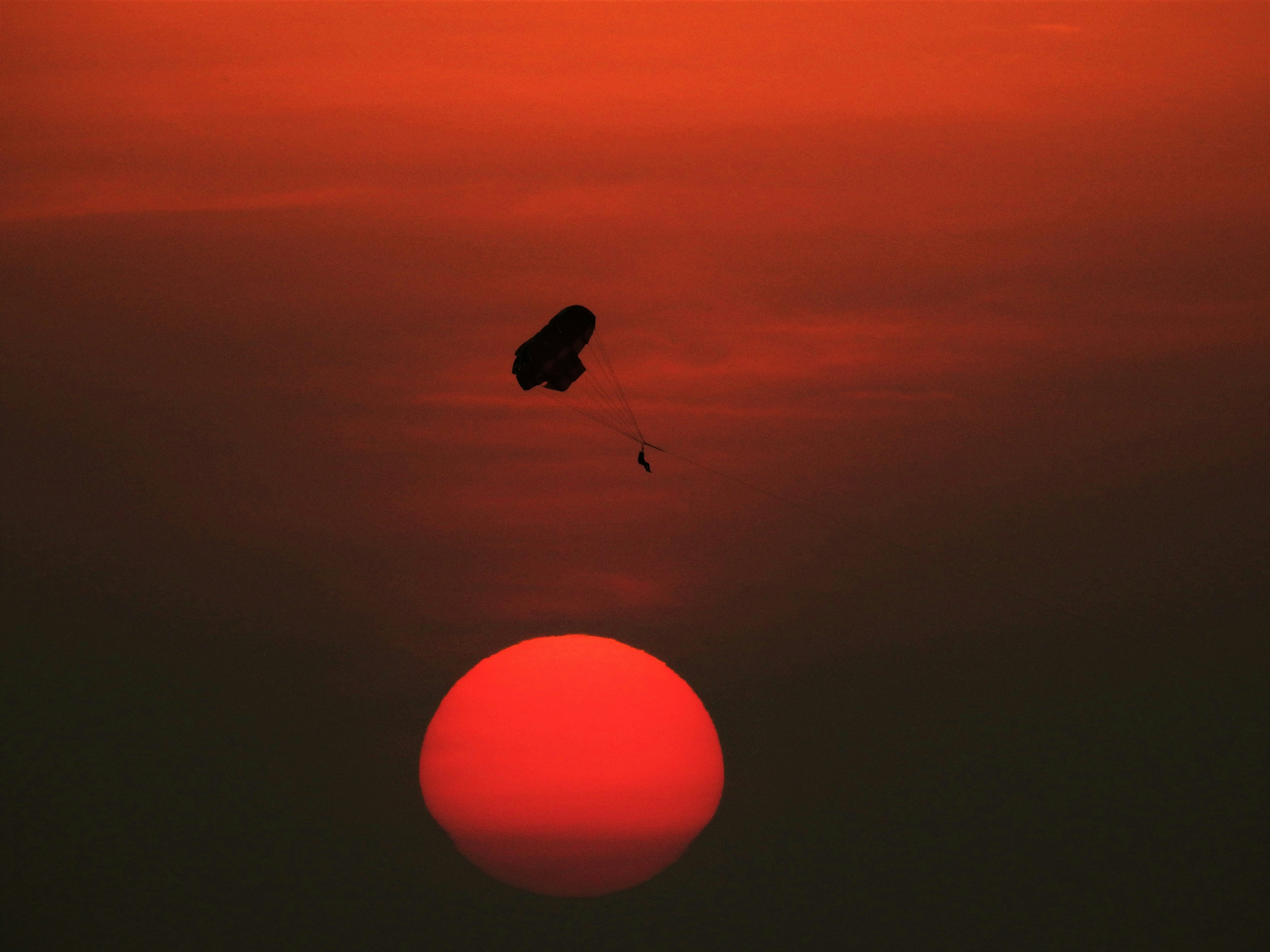 a kite flying in the sky at sunset, Sunset, paragliding, red sun.