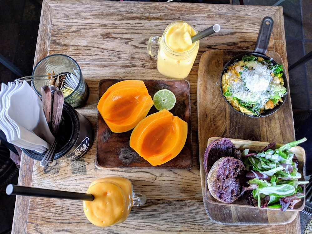 a wooden table topped with plates of food and drinks