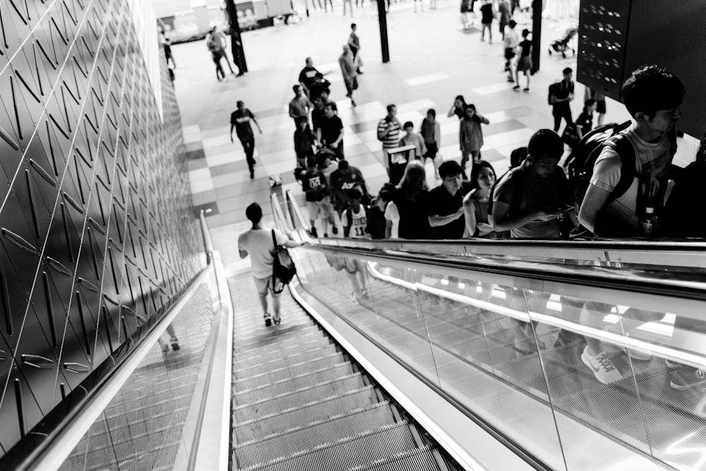 grayscale photography of people riding escaltors
