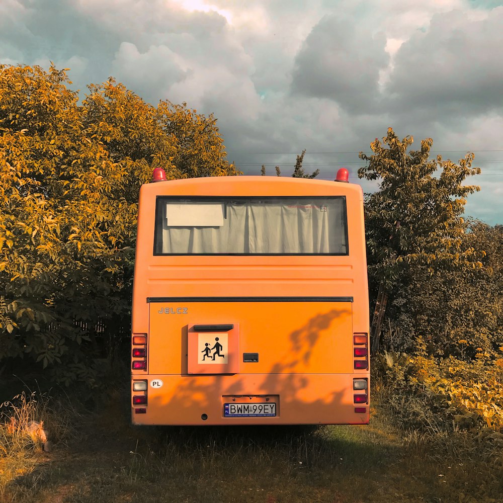 orange bus near bushes during daytime