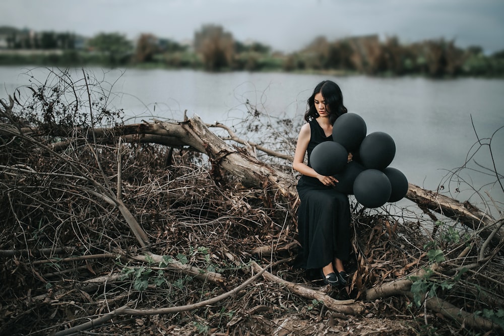 woman in black sleeveless dress holding balloons