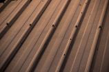 Close-up of a metal roof panel with precise seams and a subtle shine in the sunlight.