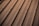 A section of a metal roof characterized by parallel lines and screws securing the panels. The surface appears smooth and reflects a warm, golden hue likely from sun exposure.
