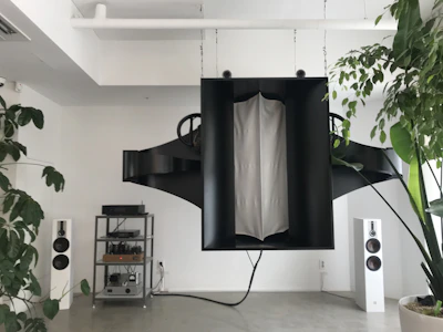 Close-up of modern sound system speakers branded with Raenas logo in a sleek indoor event space.