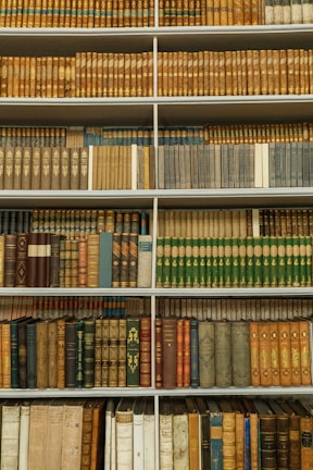 An elegant bookshelf filled with various books in soft colors.