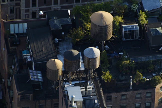 Wide shot of multiple water towers lined up on a construction yard with workers inspecting them.