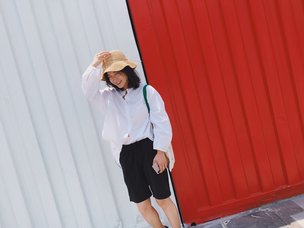 smiling woman standing beside red and white wall