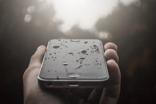 A friendly customer service representative smiling by a phone with water droplets in the background.