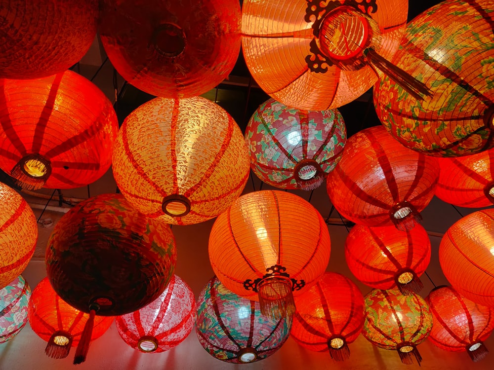 a bunch of red and orange lanterns hanging from a ceiling