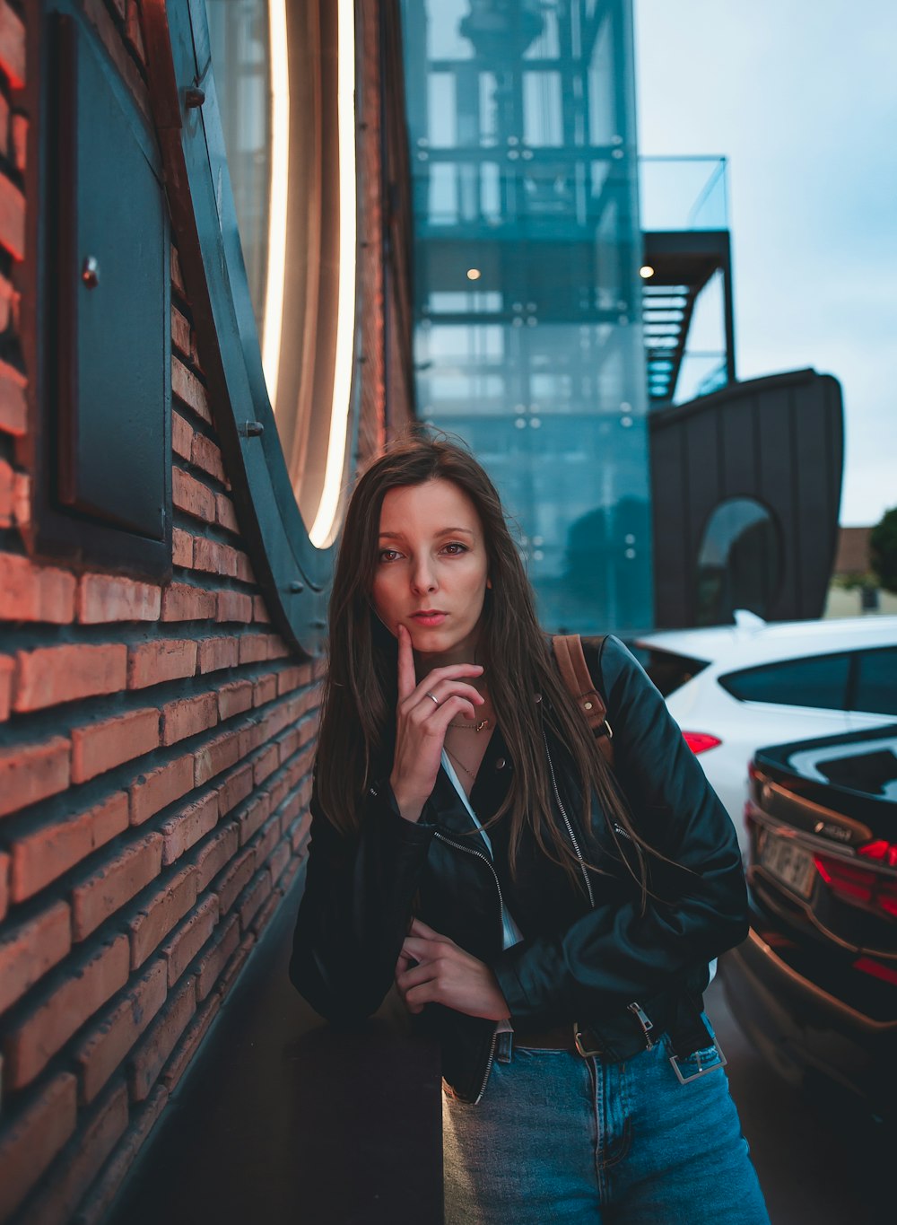 a woman leaning up against a brick wall