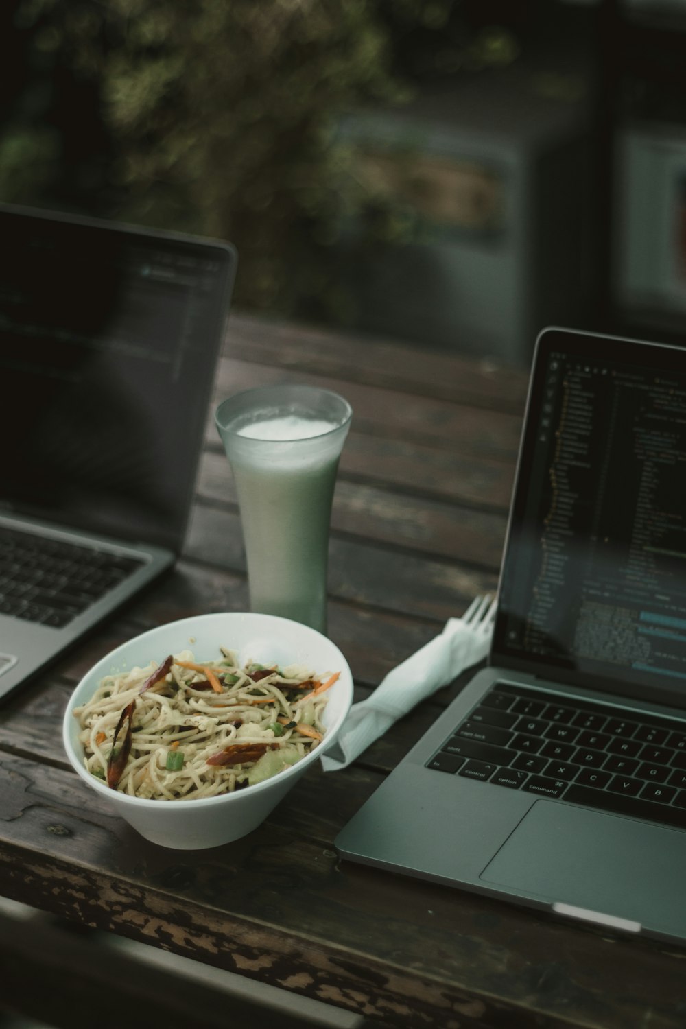 noodles on white ceramic bowl beside laptop computer