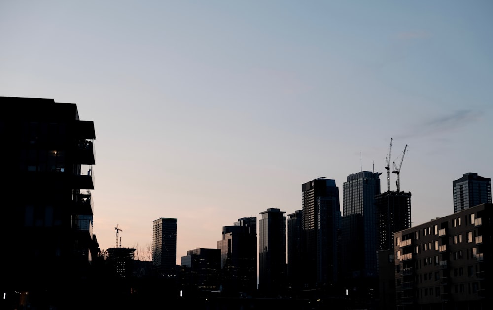 a city skyline with tall buildings and cranes