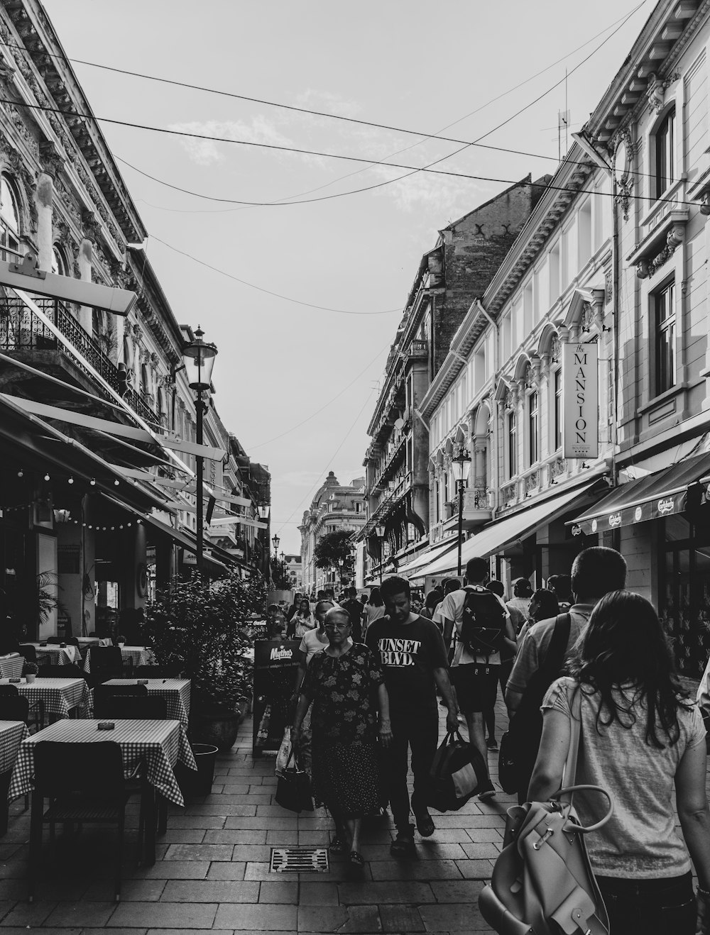 grayscale photography of people waling near buildings