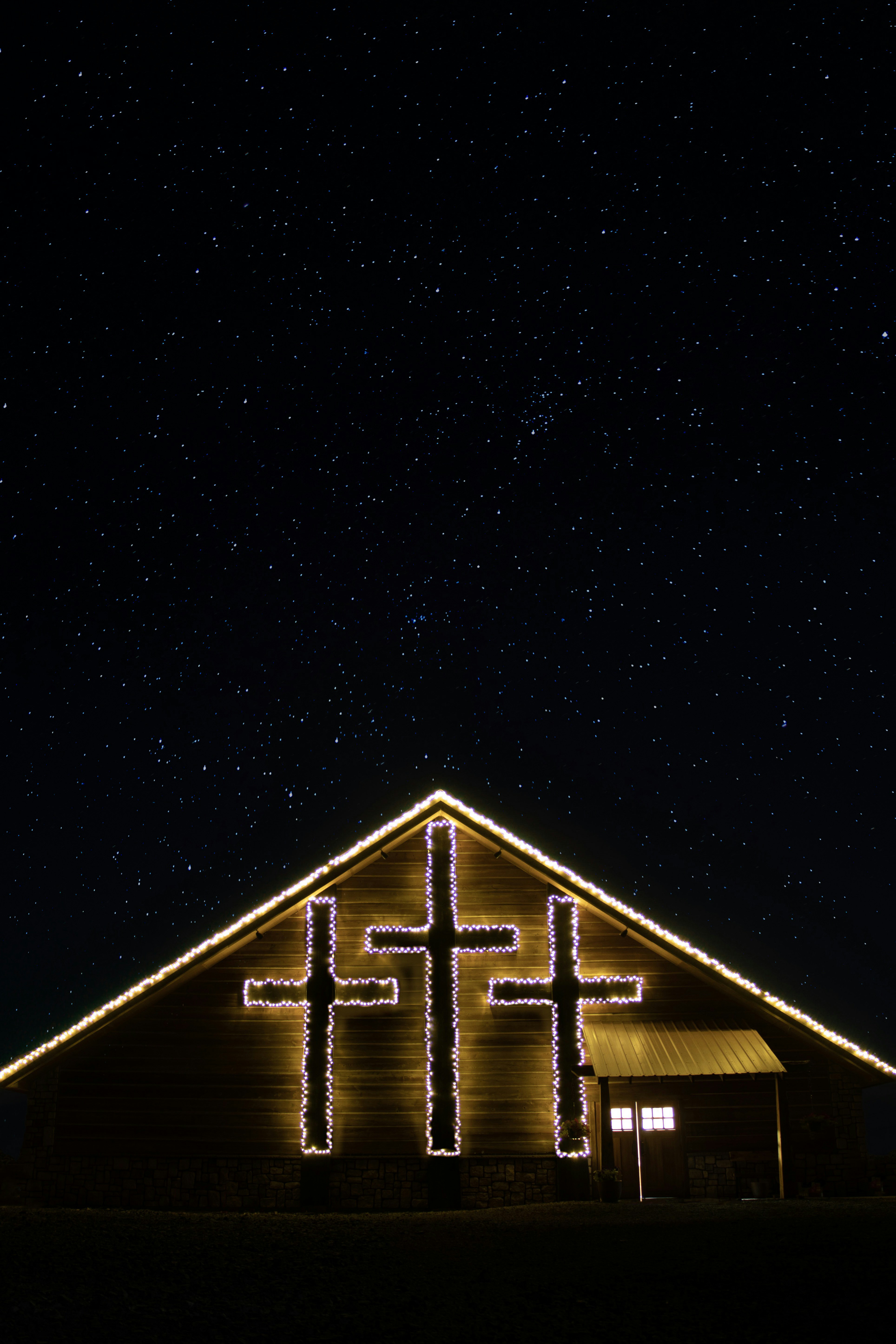 a church lit up with christmas lights under a night sky