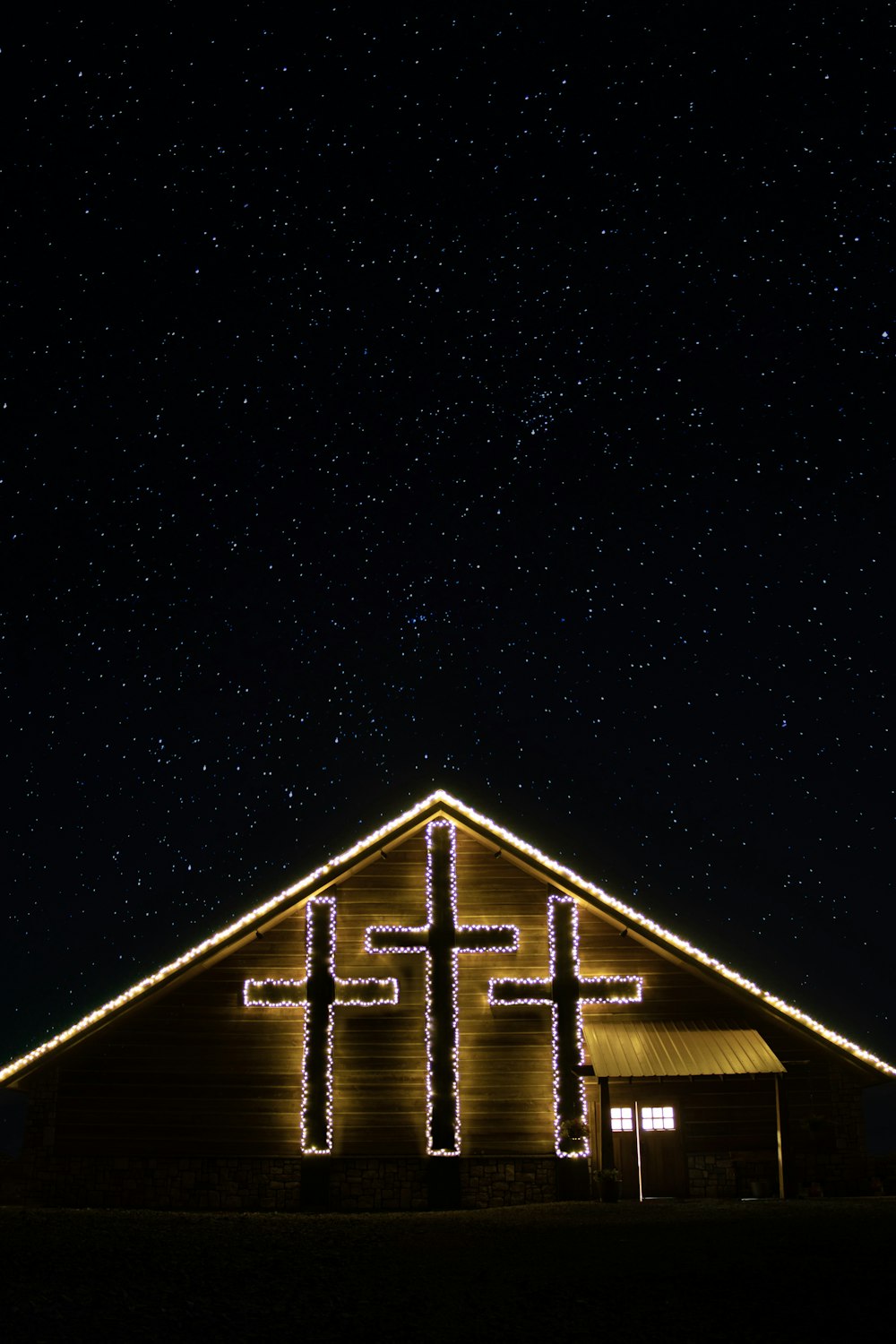 a church lit up with christmas lights under a night sky