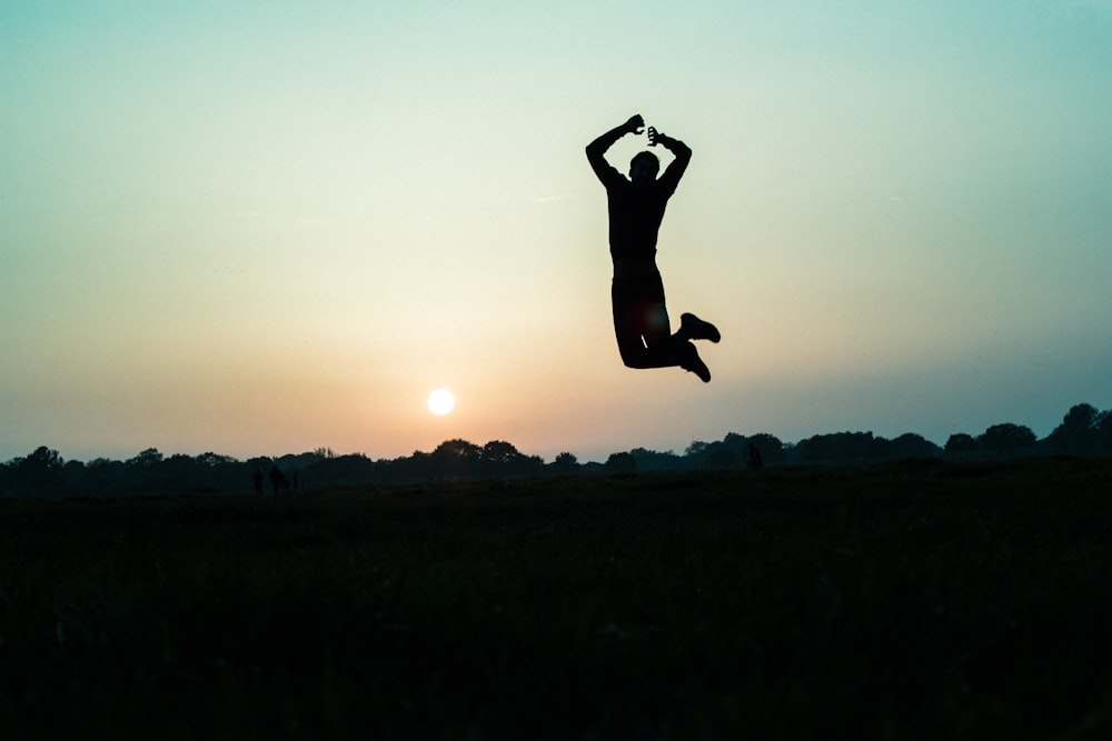 une personne qui saute en l’air au coucher du soleil