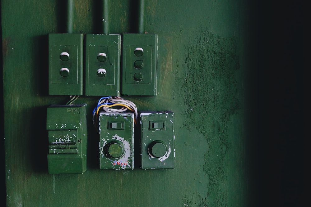 a green wall with a couple of electrical boxes attached to it