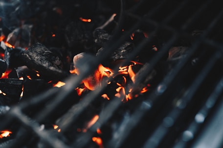 A close-up of charcoal burning in a grill, showcasing the flames.