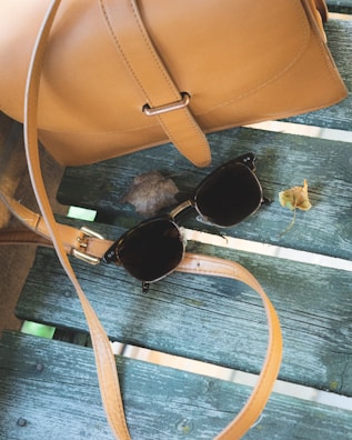 A stylish tote bag resting on a park bench with autumn leaves around.