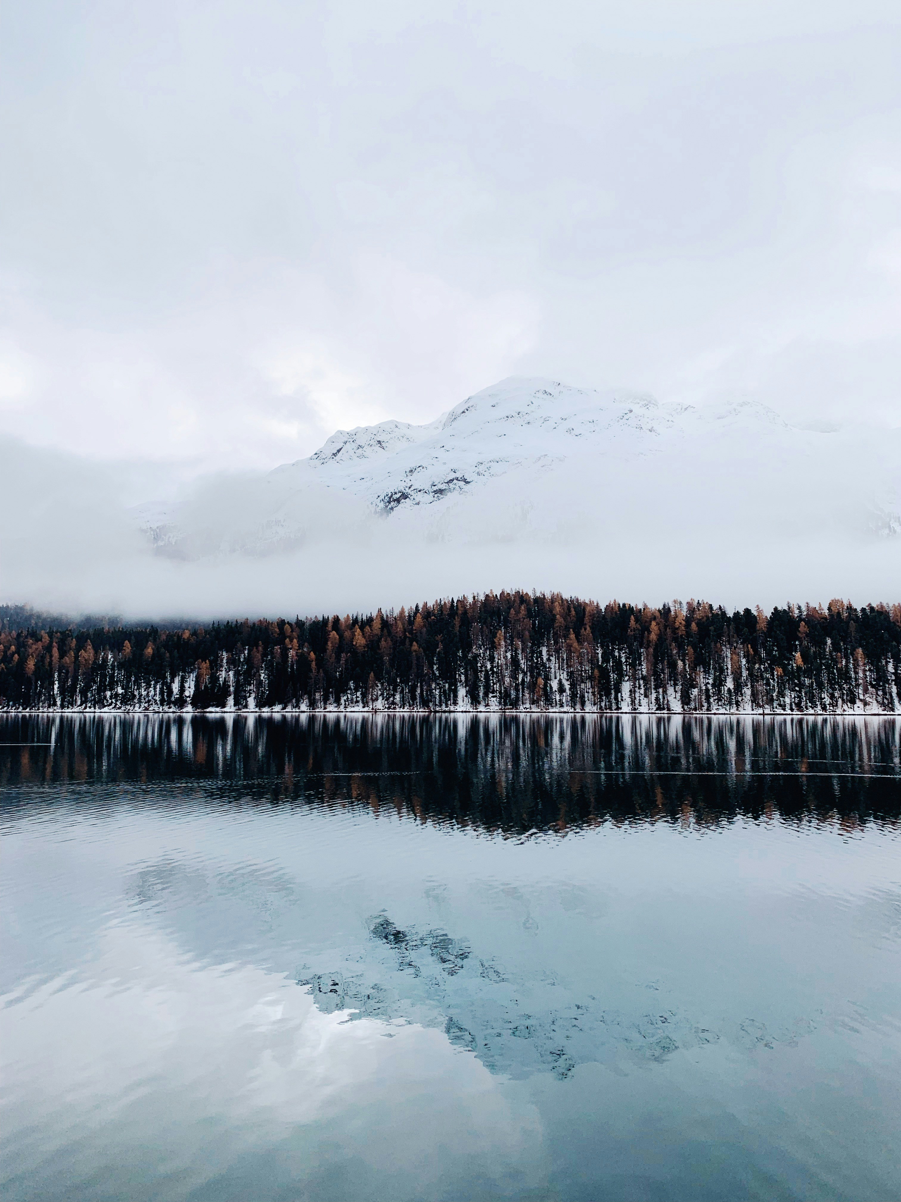 a lake surrounded by snow covered mountains and trees