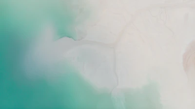 Aerial view of turquoise waters meeting white sandy shores.