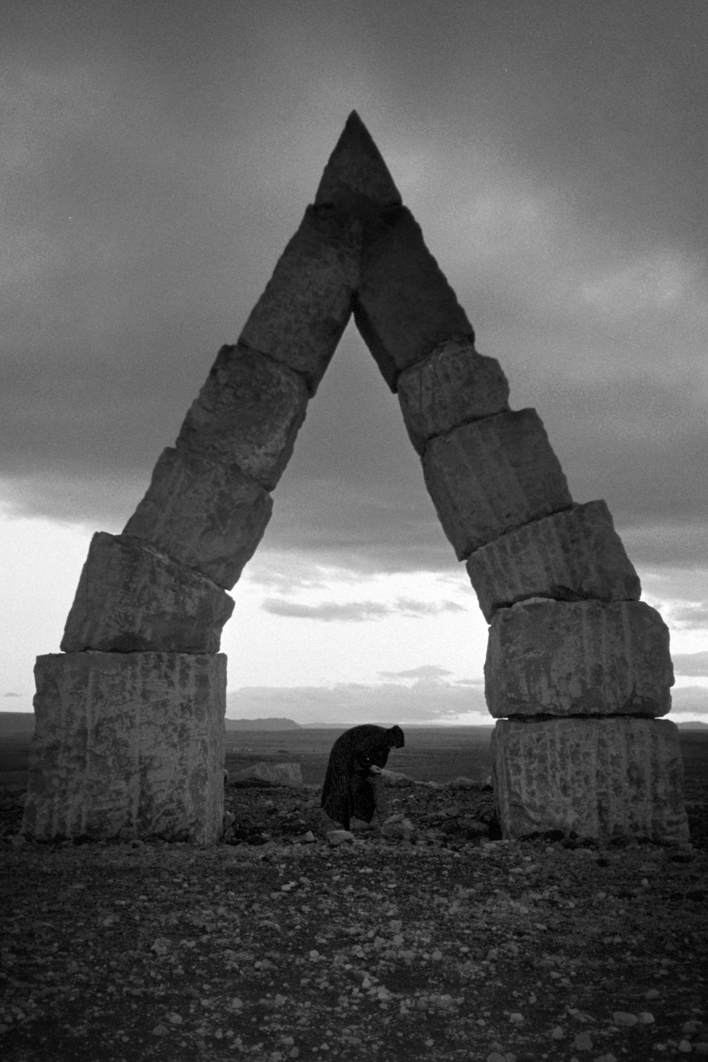 person stooping under arch monument