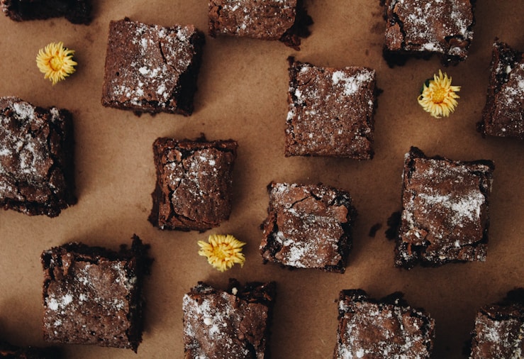 Close-up of fudgy brownies showing a stack of dense chewy chocolate squares with a glossy crinkled top and rich dark interior