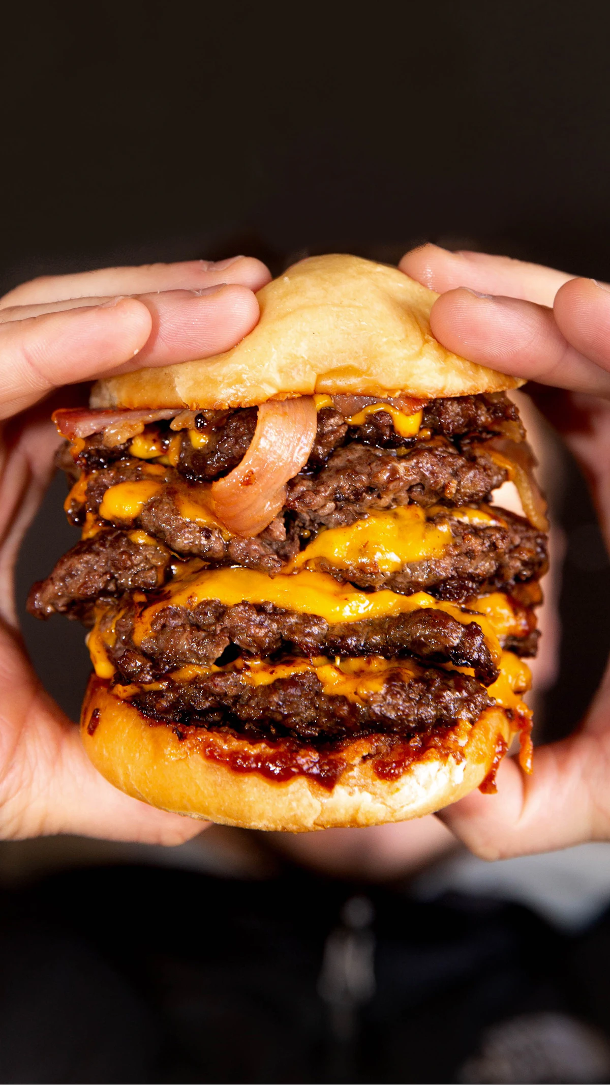 A double smashburger with crisped cheese edges, held in two hands