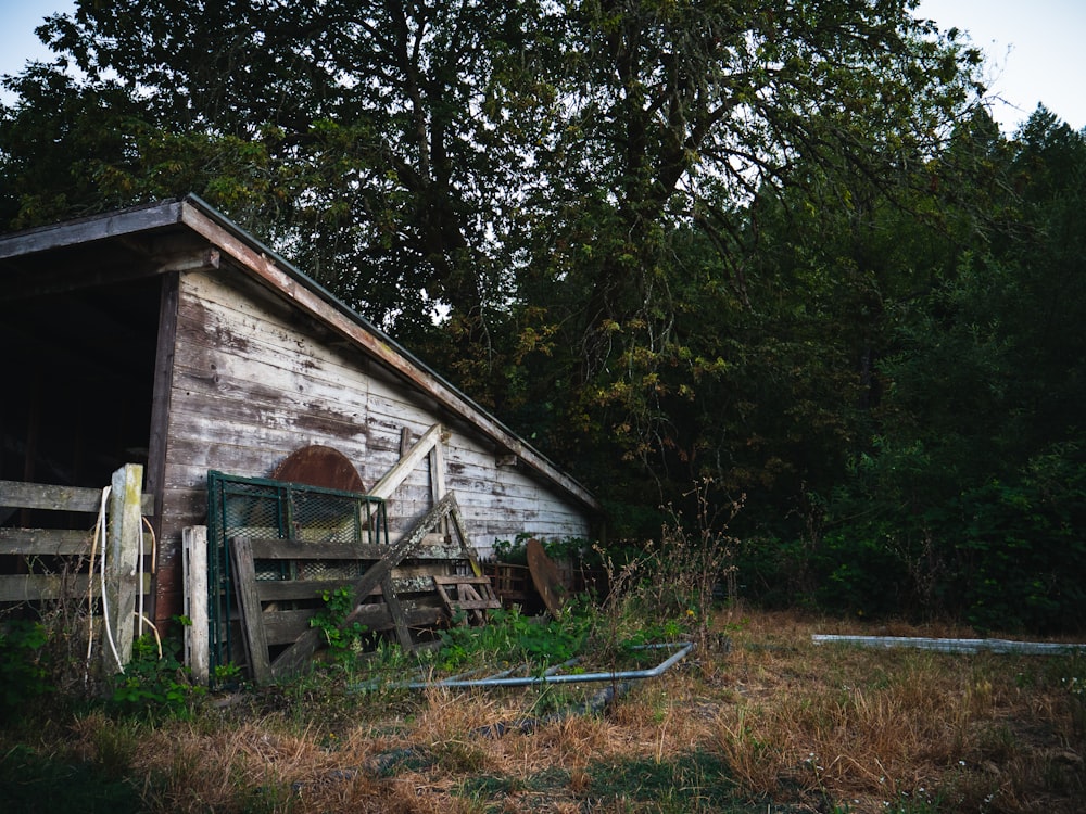 an old shed with a wheel leaning against it