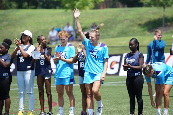 A group of diverse athletes celebrating together on a sunny sports field.