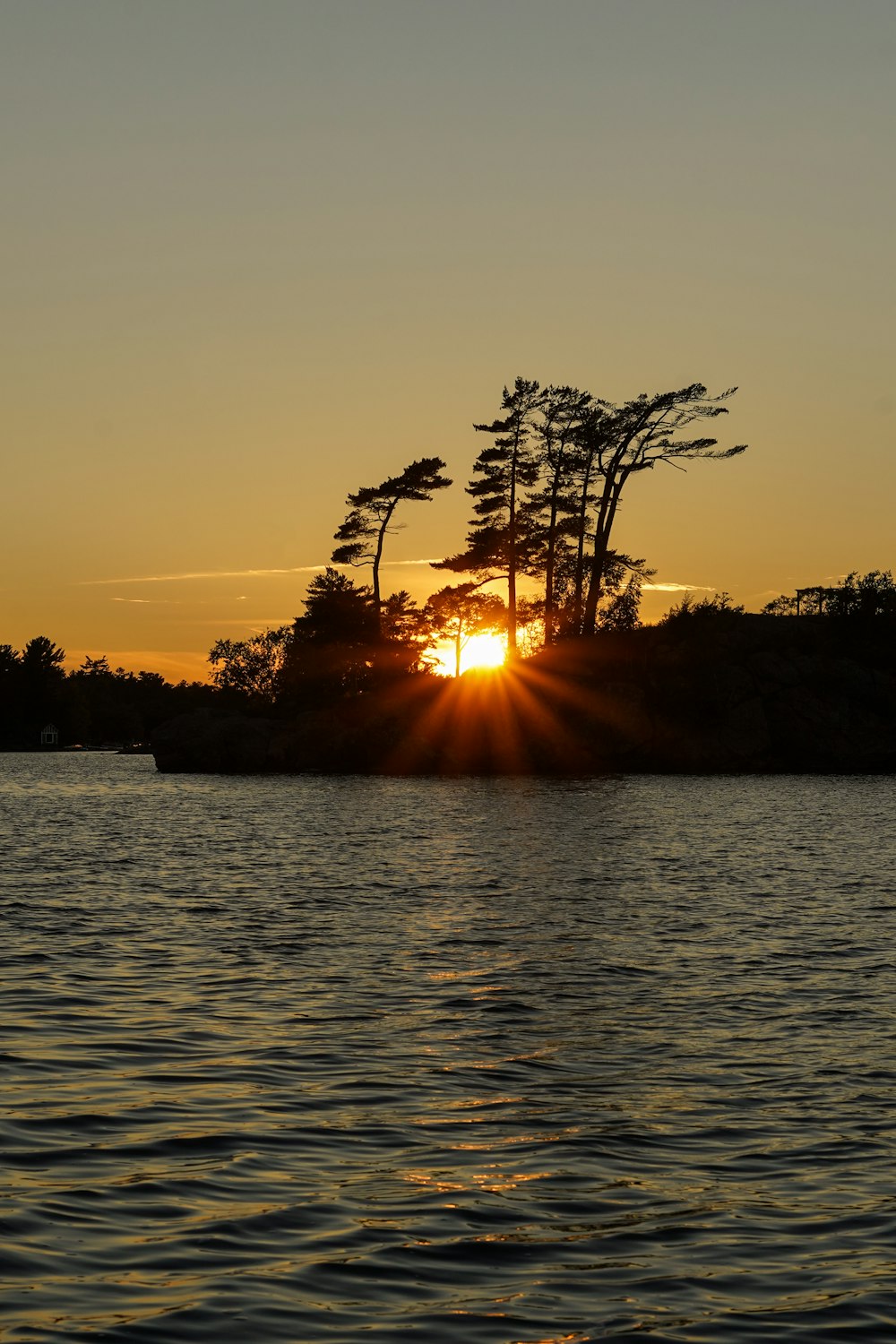 the sun is setting over a small island in the water