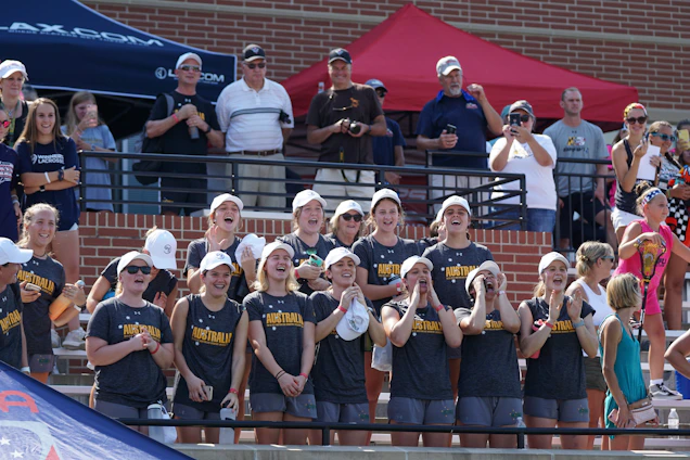 A group of focused young women in water polo gear cheering together after a game.