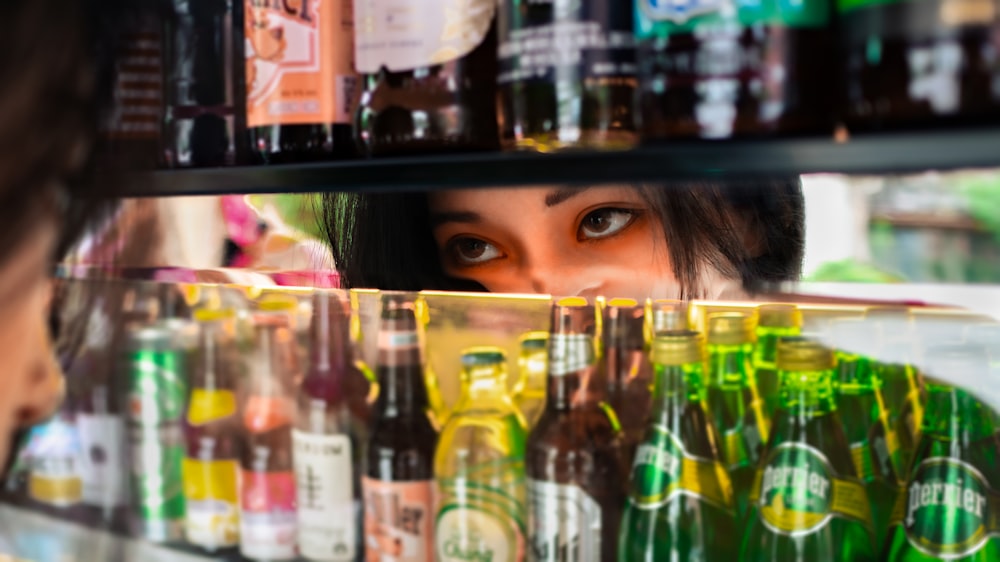 a woman looking at a shelf of beer bottles