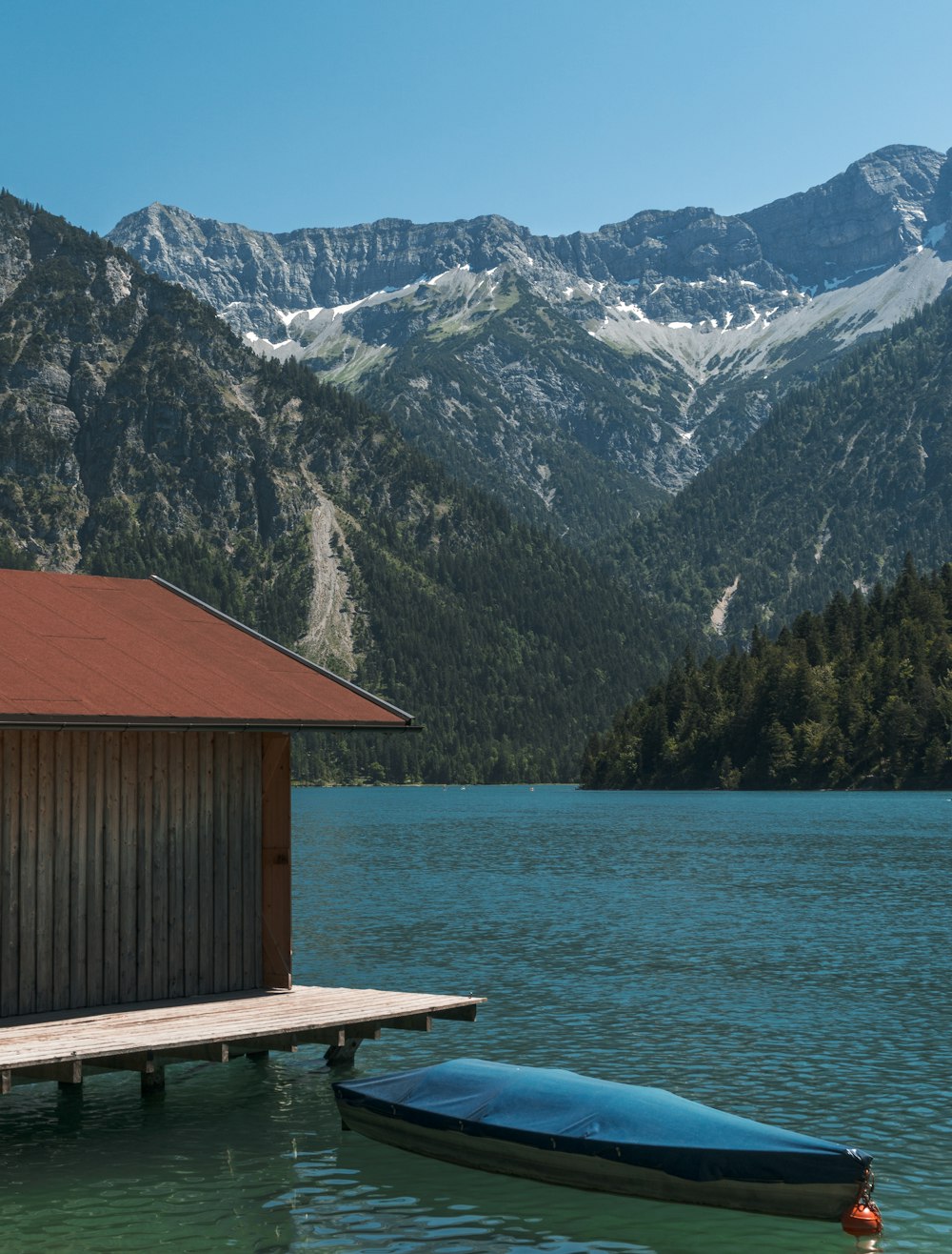 blue boat floating beside brown wooden cottage