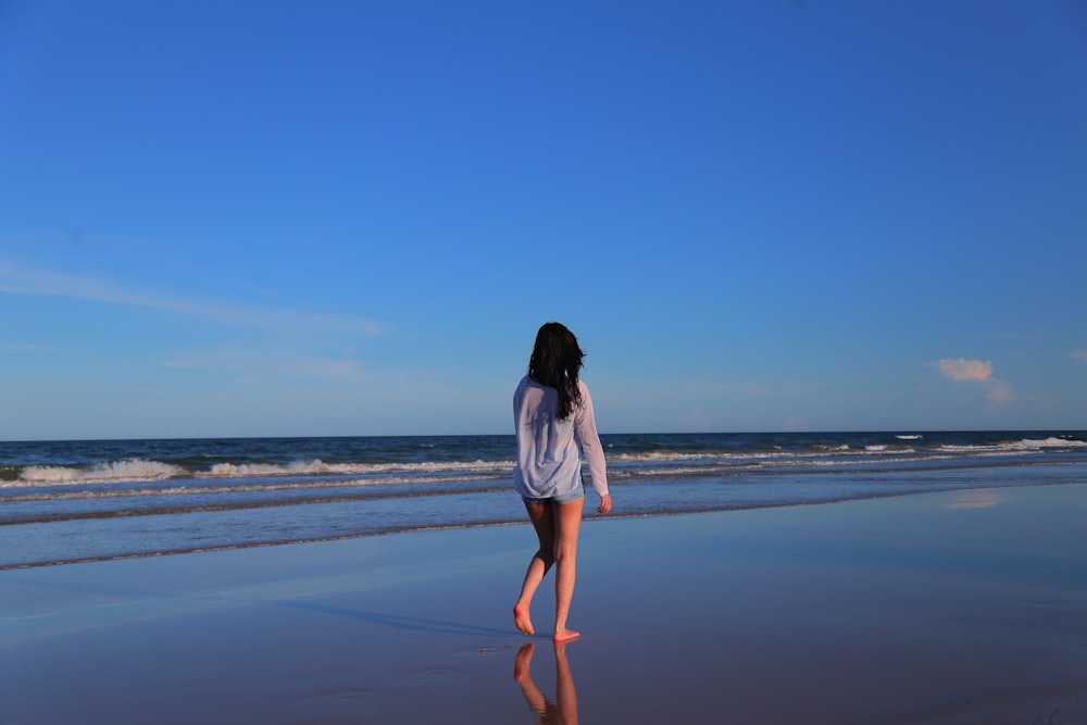 woman walking along the beach during daytime