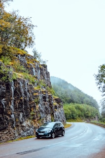 A rental car parked on a scenic road surrounded by nature.