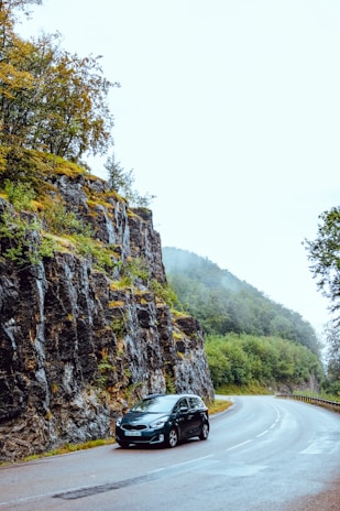 A rental car parked on a scenic road surrounded by nature.
