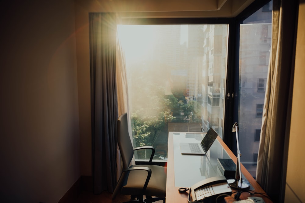 open laptop on desk near glass window